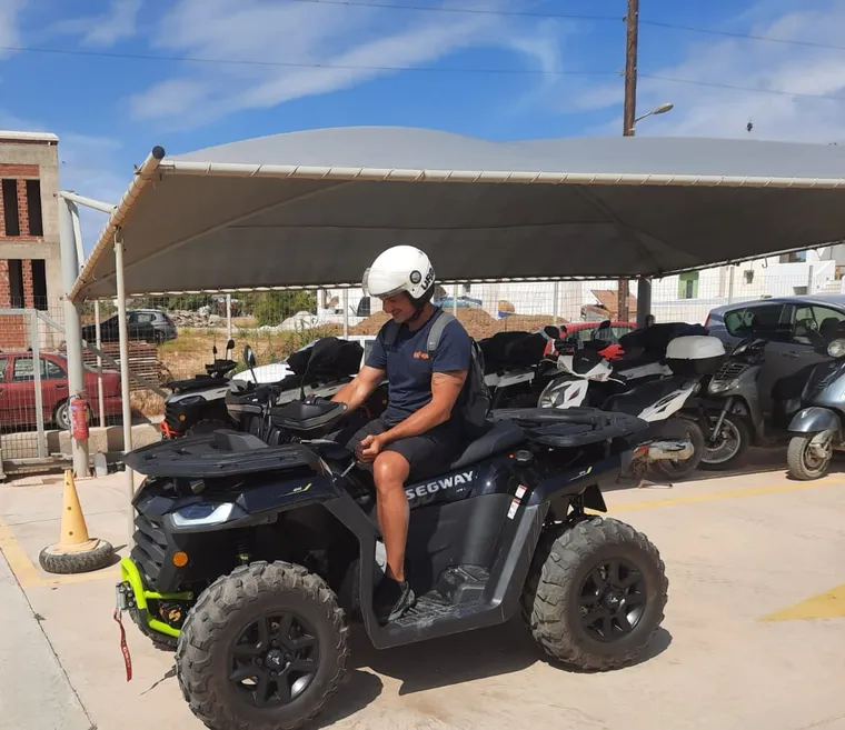 Quad rider navigating a dusty trail through olive groves